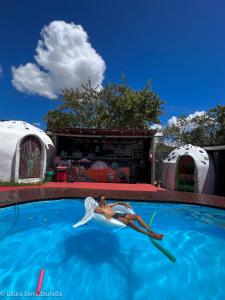 uma mulher está nadando em uma piscina em frente às tendas em Pousada Espaço Naves LunaZen em Alto Paraíso de Goiás