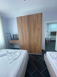 - une chambre avec 2 lits et une armoire en bois dans l'établissement A&T Apartments, à Durrës