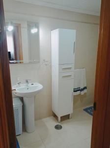 Baño blanco con lavabo y espejo en Mirador de Denia, en Denia