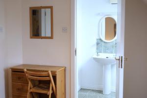 ein Bad mit einem Waschbecken, einem Schreibtisch und einem Spiegel in der Unterkunft Long Quay Apartments, Clonakilty in Clonakilty