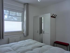 een witte slaapkamer met een bed en een raam bij Ferienwohnung H 25 "Tausendschön" in Graal-Müritz