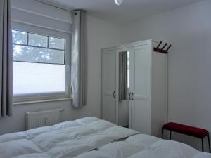 una camera da letto bianca con un letto e una finestra di Ferienwohnung H 25 "Tausendschön" a Graal-Müritz