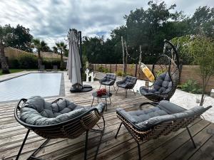 una terraza con sillas, una sombrilla y una piscina en Villa aux Palmiers,Piscine 28°,Pétanque,Coeur Bassin, en Audenge