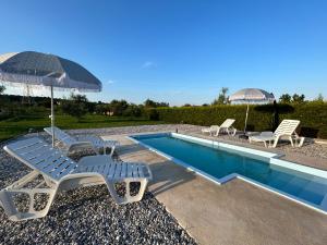 a swimming pool with chairs and umbrellas next to at Dora house with WiFi and outdoor swimming pool in Pula