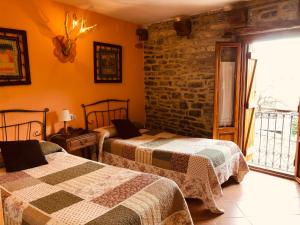 a bedroom with two beds and a brick wall at Casa Rural Basajarau in Yosa de Sobremonte