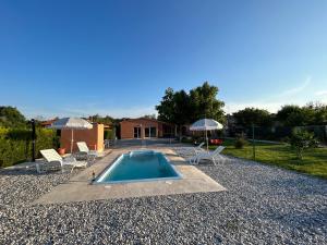 a swimming pool with chairs and umbrellas and a house at Dora house with WiFi and outdoor swimming pool in Pula