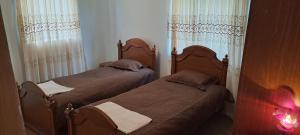 two twin beds in a bedroom with curtains at Guest house Lailashi in Surmushi