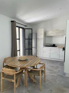 una mesa de madera y sillas en una habitación con cocina en La maison du Port Apt MARSA, en Marseillan