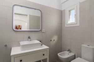 a white bathroom with a sink and a mirror at Sunset Village 2 in Paleochori