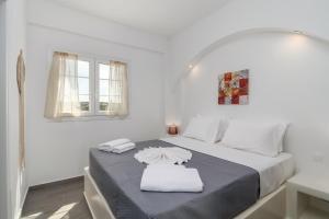 a white bedroom with a bed and a window at Sunset Village 2 in Paleochori