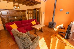 een woonkamer met een rode bank en een houtkachel bij Casa la Campa in Cardes