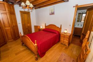 een slaapkamer met een houten bed met een rode sprei bij Casa la Campa in Cardes