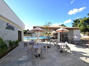 eine Terrasse mit Tischen, Stühlen und Sonnenschirmen neben einem Pool in der Unterkunft DiRoma Resort / Splash e Acqua Park in Caldas Novas