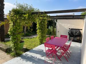 a red table and chairs sitting under a pergola at Kerhoki in Le Vivier-sur-Mer