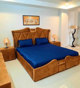 a large bed with blue sheets and blue pillows at Anabi Apartments and Suits E11 Islamabad in Islamabad