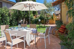 - une table et des chaises avec un parasol dans la cour dans l'établissement La Villa di Tenute Foti Randazzese, à Nicolosi