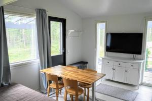 een eetkamer met een houten tafel en een televisie bij Cozy 4 person guesthouse on quiet residential area in Oulu