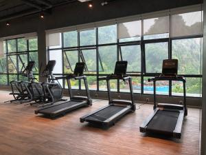 a gym with a row of treadmills in a room with windows at Onsen Oasis Premium Suites in Tambun