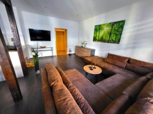 una sala de estar con un gran sofá marrón y una mesa. en Ferienwohnung SehrGemütlich, en Lichtenstein
