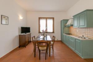 ボルゲリにあるOsteria Vecchia 6のキッチン(緑のキャビネット、テーブル、椅子付)
