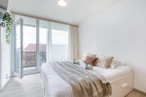 een witte slaapkamer met een groot bed en een groot raam bij Cosy studio near the beach in Oostende
