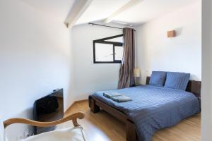 Schlafzimmer mit einem Bett mit blauer Bettwäsche und einem Fenster in der Unterkunft Grand Appartement De Standing in Seignosse