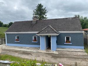 a blue house with two windows and a roof at Clinton’s cottage in Leitrim