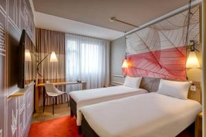 ニュルンベルクにあるイビス ニュルンベルク セントルム アム プレラーのベッド2台とデスクが備わるホテルルームです。