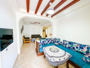 ein Wohnzimmer mit einem blauen Sofa und einem Tisch in der Unterkunft Grand appartement en face à la mer avec piscine. in Oued Laou
