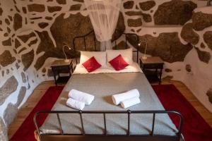 a bedroom with a bed with red and white pillows at Quinta da Lontra in Tábua