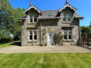 une ancienne maison en pierre avec une porte blanche dans l'établissement Luxury Garden Cottage, à Dalry