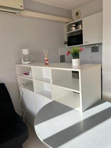 a white desk with a microwave and flowers in a room at Studio residence de tourisme le Fonserane in Béziers