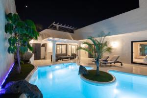 - une piscine dans une maison avec des palmiers dans l'établissement Bahiazul Resort Fuerteventura, à Corralejo