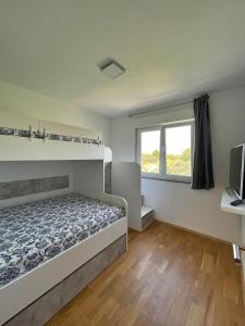 een slaapkamer met een bed, een televisie en een raam bij Apartments Ursula 3 in Trogir