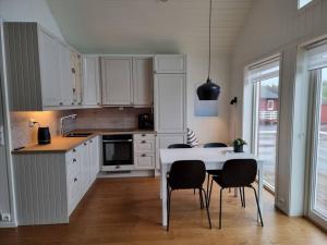 a kitchen with white cabinets and a table and chairs at Stambua, Stamsund in Stamsund