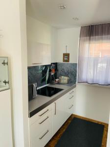 uma cozinha com armários brancos, um lavatório e uma janela em Hiška Orel Terme Čatež em Čatež ob Savi