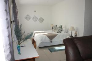 1 dormitorio con 1 cama y 1 sofá en Eucalyptus Cottage en Ciudad del Cabo