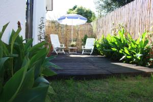 un patio con 2 sillas y una sombrilla en Eucalyptus Cottage, en Ciudad del Cabo