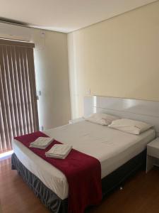 a bedroom with a bed with a red blanket on it at Flor Que Ri - Flats Mobiliados na Melhor Localização in Olímpia
