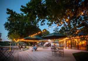 a patio with tables and chairs and lights at night at Huttopia Lac de Rillé in Rillé