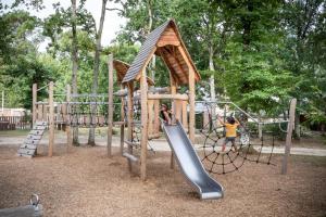 two children playing on a playground with a slide at Village Huttopia Lac de Rillé in Rillé