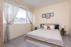 een witte slaapkamer met een groot bed en een raam bij Cozy home next to Aliosha in Plovdiv