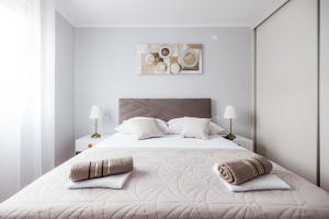 een witte slaapkamer met een groot wit bed met 2 kussens bij Bridge Comfort Apartment in Zadar