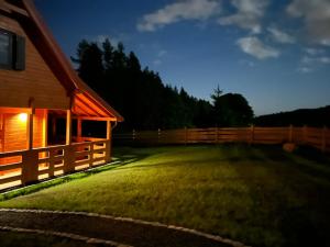 un cortile di notte con recinzione e casa di Okno na las a Polanica-Zdrój