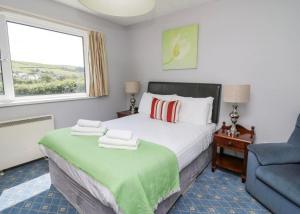 a bedroom with a bed and a chair and a window at Aberceiro Bungalow in Aberystwyth