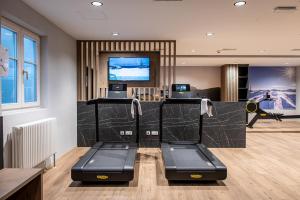 einen Fitnessraum mit einer Bank und einem TV in einem Zimmer in der Unterkunft HOTEL POST alpine cityflair in Bruneck