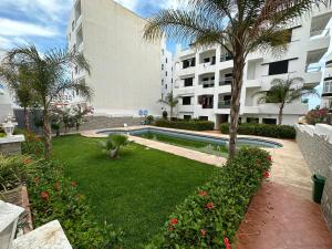 un patio del complejo con piscina y palmeras en Grand appartement en face à la mer avec piscine. en Oued Laou