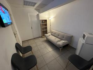 sala de estar con sofá, sillas y TV en AZUR HOTEL en Saint-Denis