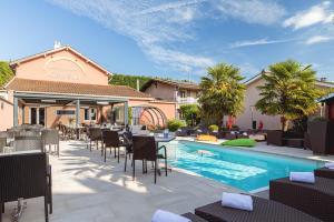 un patio con mesas y sillas junto a una piscina en Contact Hôtels Les Pierres Dorées, en Ambérieux d'Azergues