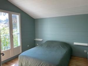 a blue bedroom with a bed and a window at Charmante maison aux Abatilles-piscine-8 pers in Arcachon +13 photos